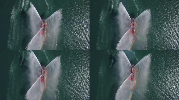 一艘漂浮的现代船舶喷射水柱，展示消防水枪，从无人机俯视消防艇喷水