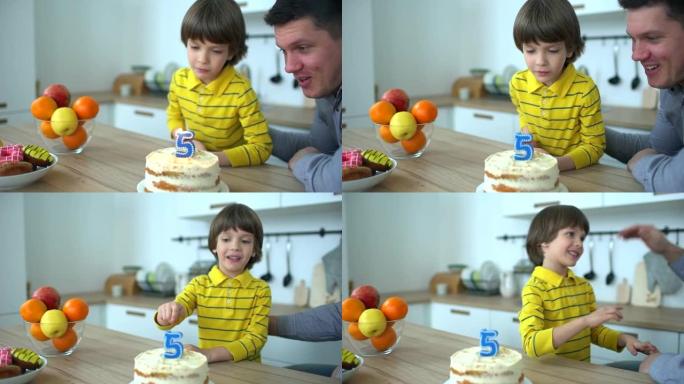 非常可爱的男孩用蛋糕和快乐的父亲庆祝他的生日。5年生日快乐。父亲节。小男孩在家吹灭生日蛋糕上的蜡烛。