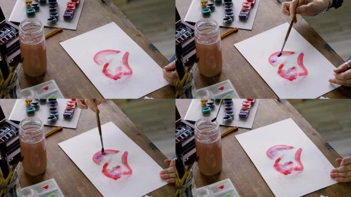 女艺术家的手的特写镜头用水彩画了一颗红色的心。4K