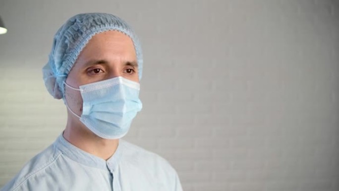大流行期间戴着防护口罩的男医生。一个疲惫的医生的特写肖像。特写。点头和拒绝的手势。