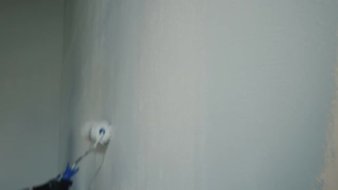 两个人用油漆滚筒粉刷墙壁