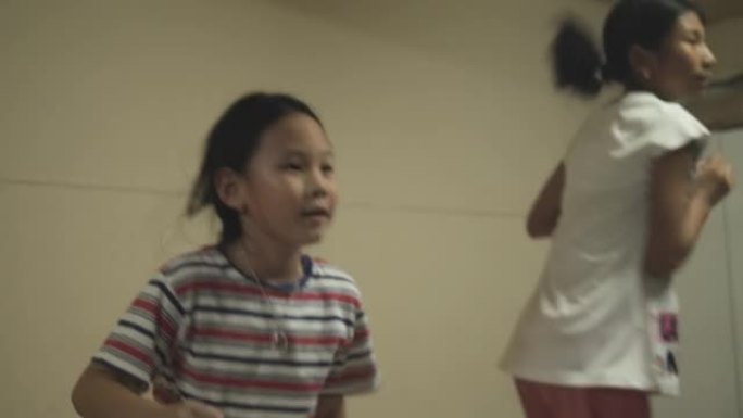 快乐的亚洲女孩一起在床上唱歌跳舞，在家活动的理念。