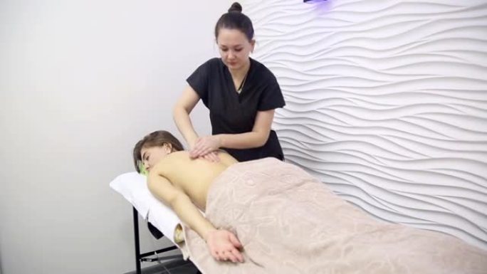 肩胛骨区域患者背部按摩，女按摩师