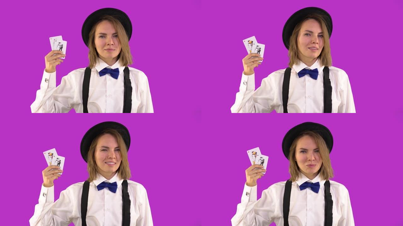 穿着白衬衫和帽子的副主持人展示了扑克牌和微笑。小丑卡。紫色背景，工作室