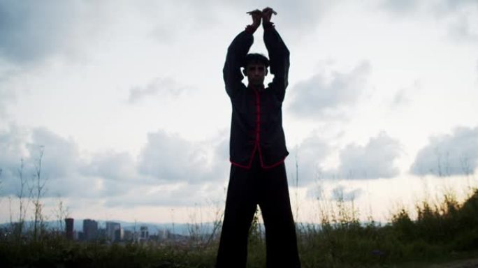男人在大自然的日落中练习中国体操或志功