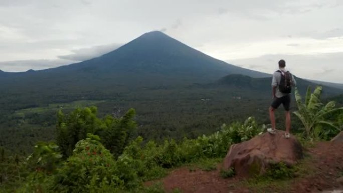 男子奔向巴厘岛雨林上方阿贡山的监视点。游客看着印度尼西亚丛林上方的大山峰