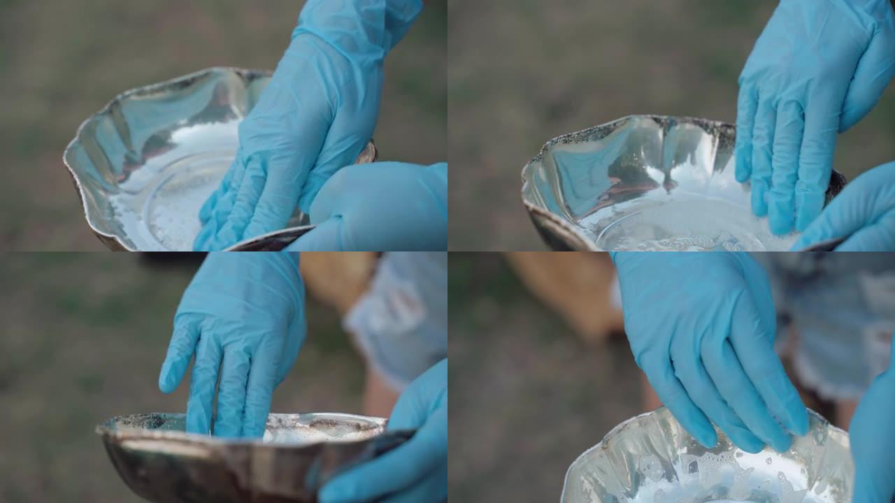用闪亮的抛光剂清洗古董银板的过程，在防护手套上擦拭银碗表面进行铁锈清洗。银色物品、复古器皿的抗氧化作