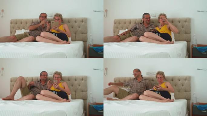 当成熟的夫妇坐在酒店房间的床上时，他们会使用智能手机在线下订单。