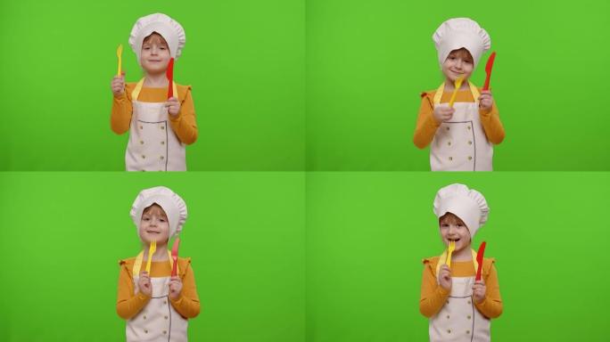 女童穿着厨师用叉子和刀子做饭，在色度关键背景上挥舞着头部认可