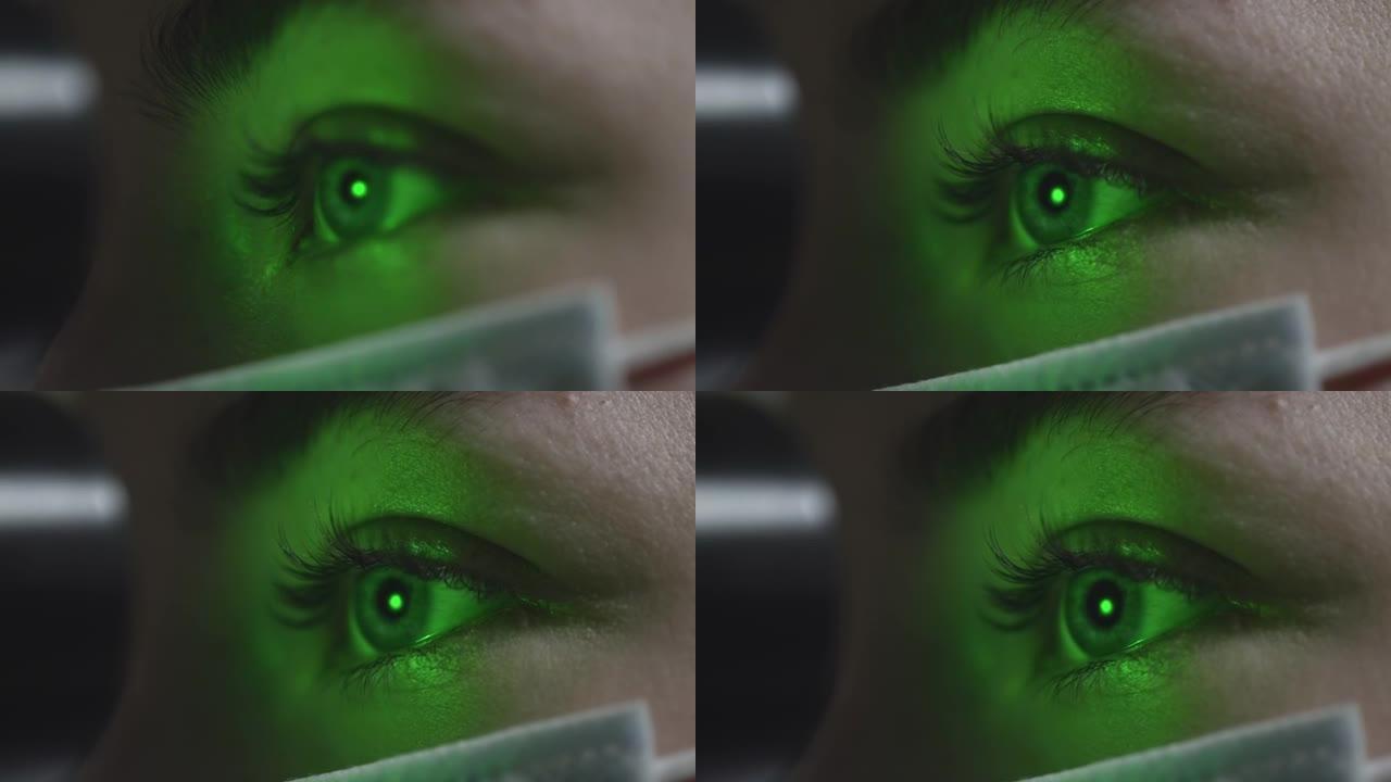 MACRO:一位戴着医用口罩的妇女在与眼科医生预约时检查眼睛。一束绿色的激光射进瞳孔。眼科治疗-一位