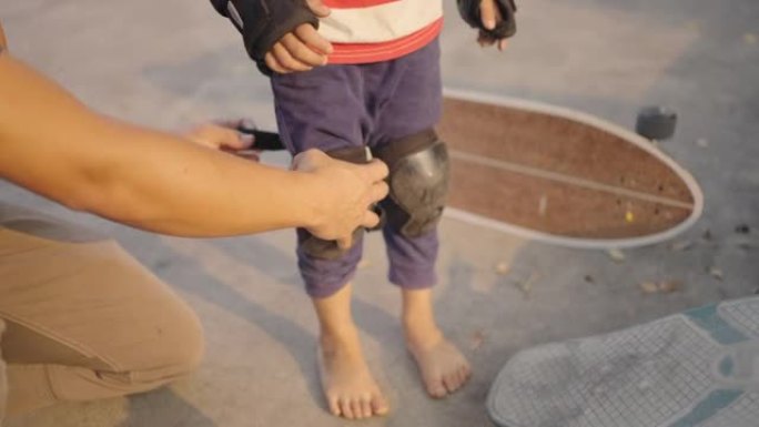 男子帮助孩子在滑板前戴防护护膝。