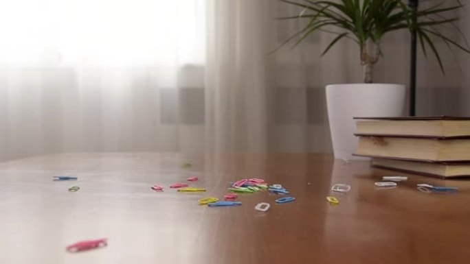 彩色回形针落在桌子上。慢动作视频。