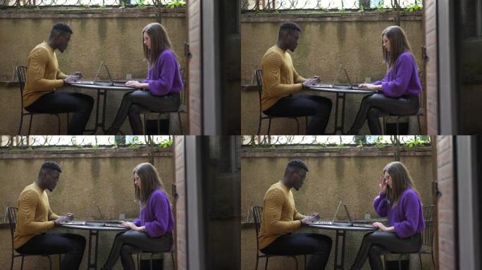 多样化的夫妇在家在笔记本电脑前工作，在外面工作