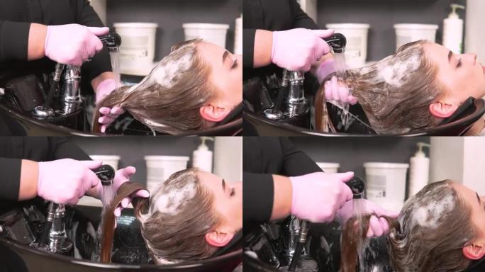 戴着手套的美发师在脸盆中洗掉客户头发上的洗发水