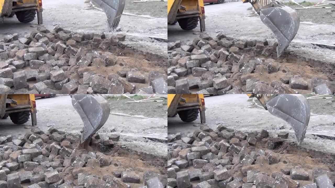挖掘机用铲斗清除道路上的旧铺路石