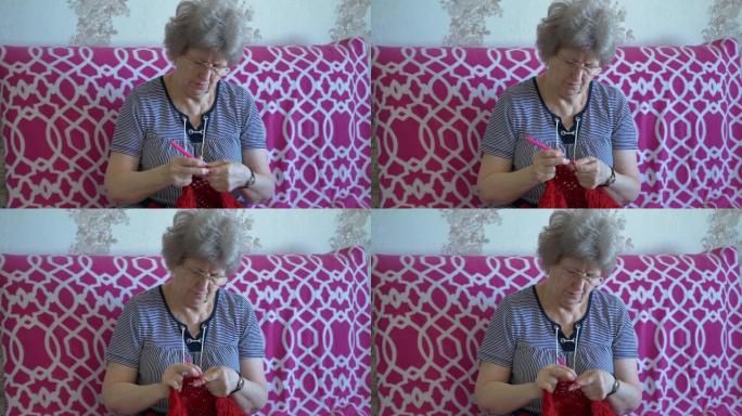 戴眼镜的祖母用红线钩针编织
