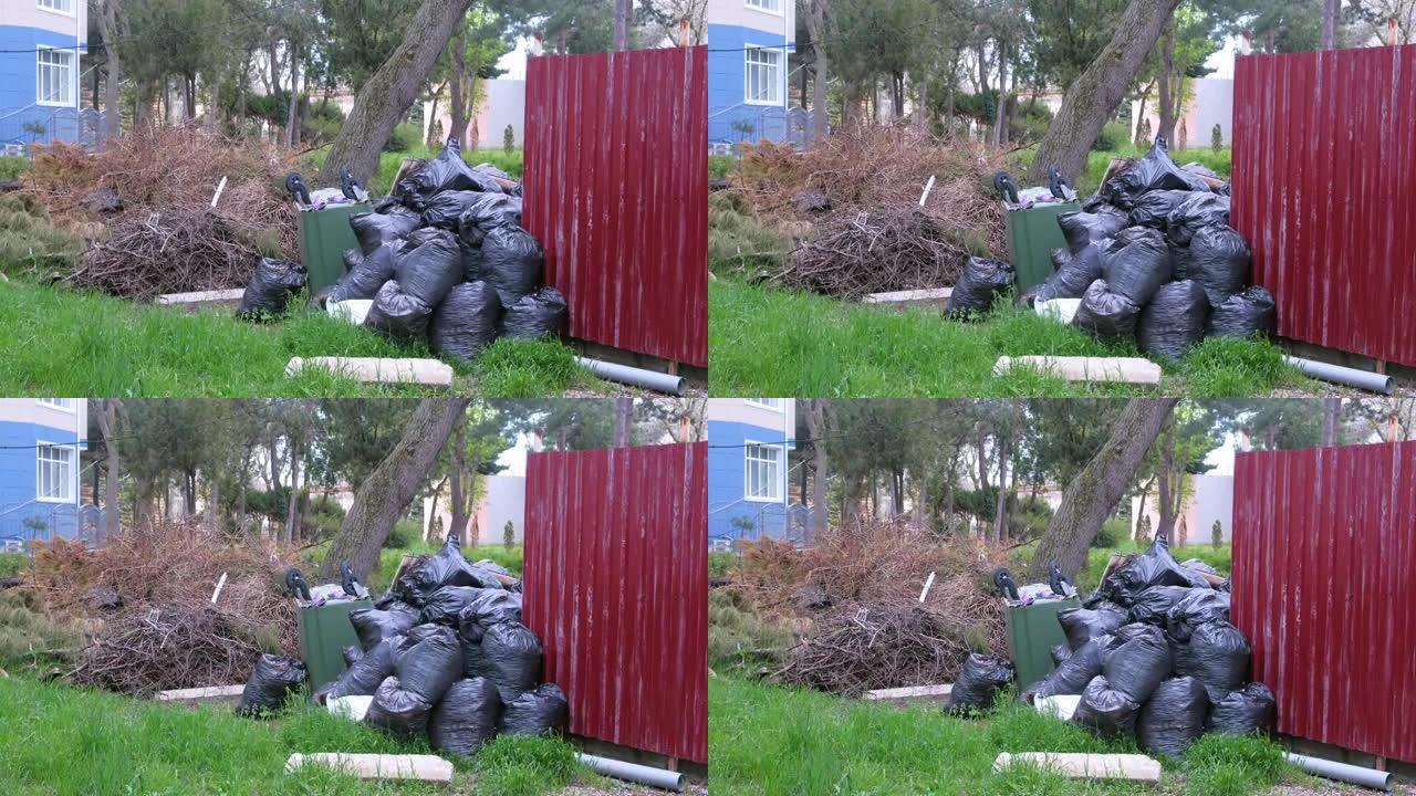 私人住宅围栏附近的黑色垃圾袋和一个翻倒的垃圾桶。