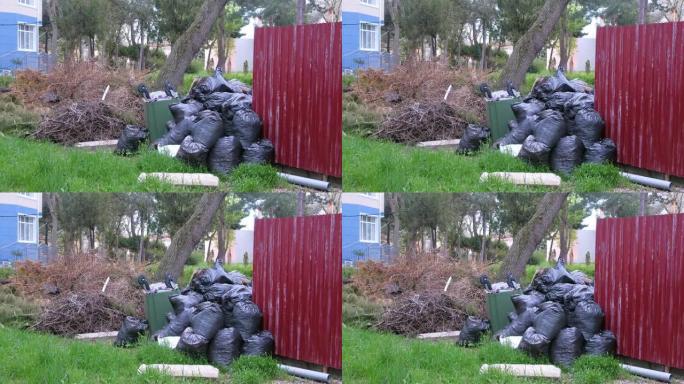 私人住宅围栏附近的黑色垃圾袋和一个翻倒的垃圾桶。