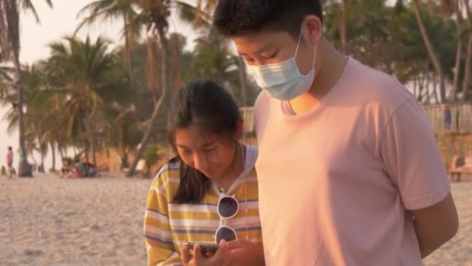 快乐的亚洲儿童一起在海滩上自拍后在智能手机上看照片，生活方式概念。