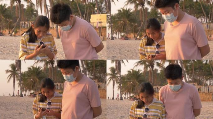 快乐的亚洲儿童一起在海滩上自拍后在智能手机上看照片，生活方式概念。