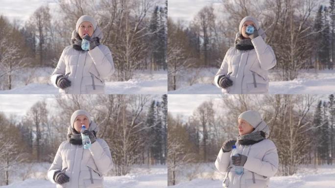 寒冷的日子里，孕妇在冬季公园用塑料瓶喝水