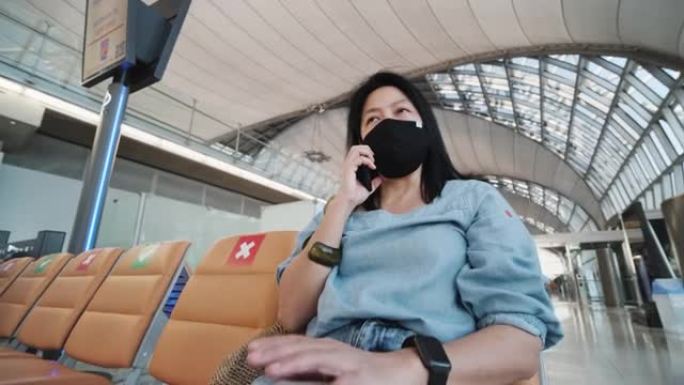 亚洲女性旅行者在机场航站楼等待出发时使用手机当旅行泡沫在新的正常生活方式中
