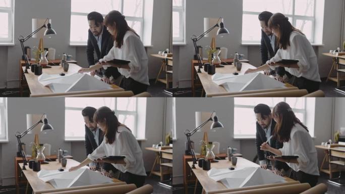 两名亚洲建筑师规划景观建设并在数字平板电脑上做笔记的中景