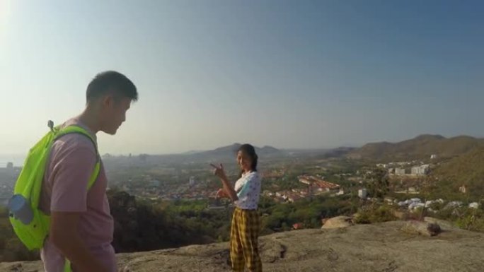 快乐的亚洲女孩跳舞，与她的兄弟在山顶上制作病毒视频TikTok，用太阳光，时尚的生活方式概念。