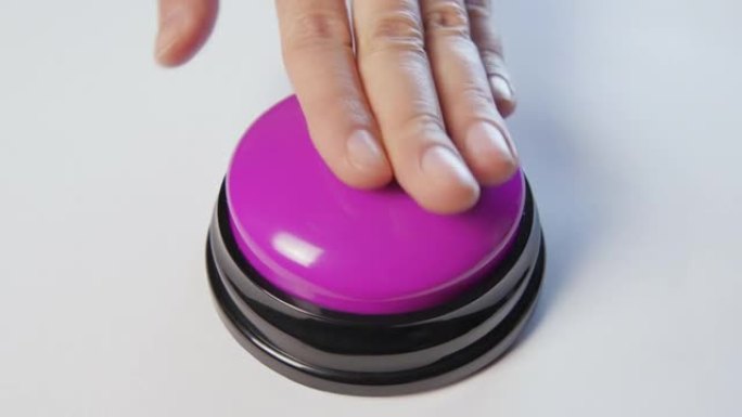 年轻女子用手指和手掌推动紫色按钮。按下圆形光泽按钮，俯视图。激活，发射一些东西。打开和关闭。