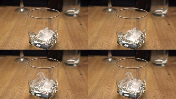 将冰块放入木制桌子上的玻璃杯中。