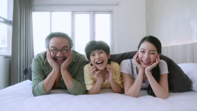 快乐的亚洲家庭可爱，孩子和家庭的概念 -- 快乐的家庭和小儿子在毯子下白色舒适的床上，父母在家