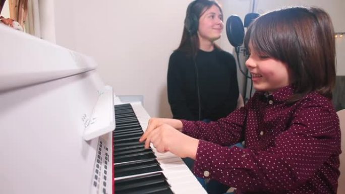 开朗的孩子用手指弹钢琴歌手她用麦克风唱歌。