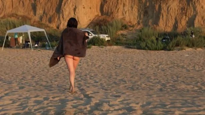 女人在日落时用毛巾擦干自己的身体