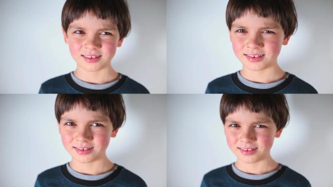白色背景上的儿童肖像男孩眯着眼睛，看着相机。