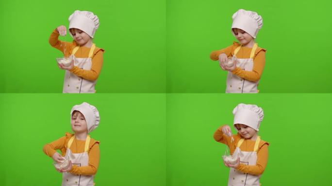 穿着围裙和帽子的童女小孩厨师贝克在盘子里搅拌面粉，鬼混