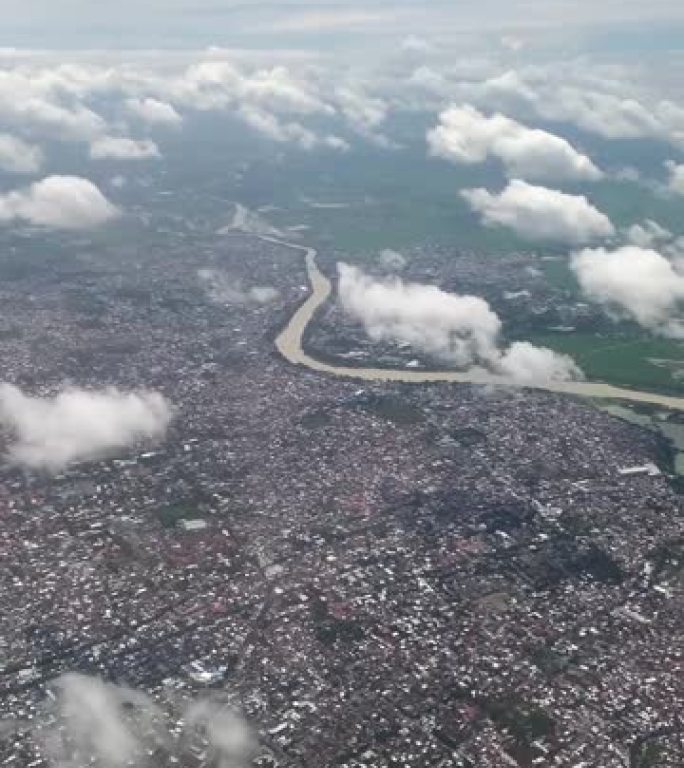 从天空中飞过云层的飞机上可以看到城市。飞机窗户上美丽风景的垂直视频。