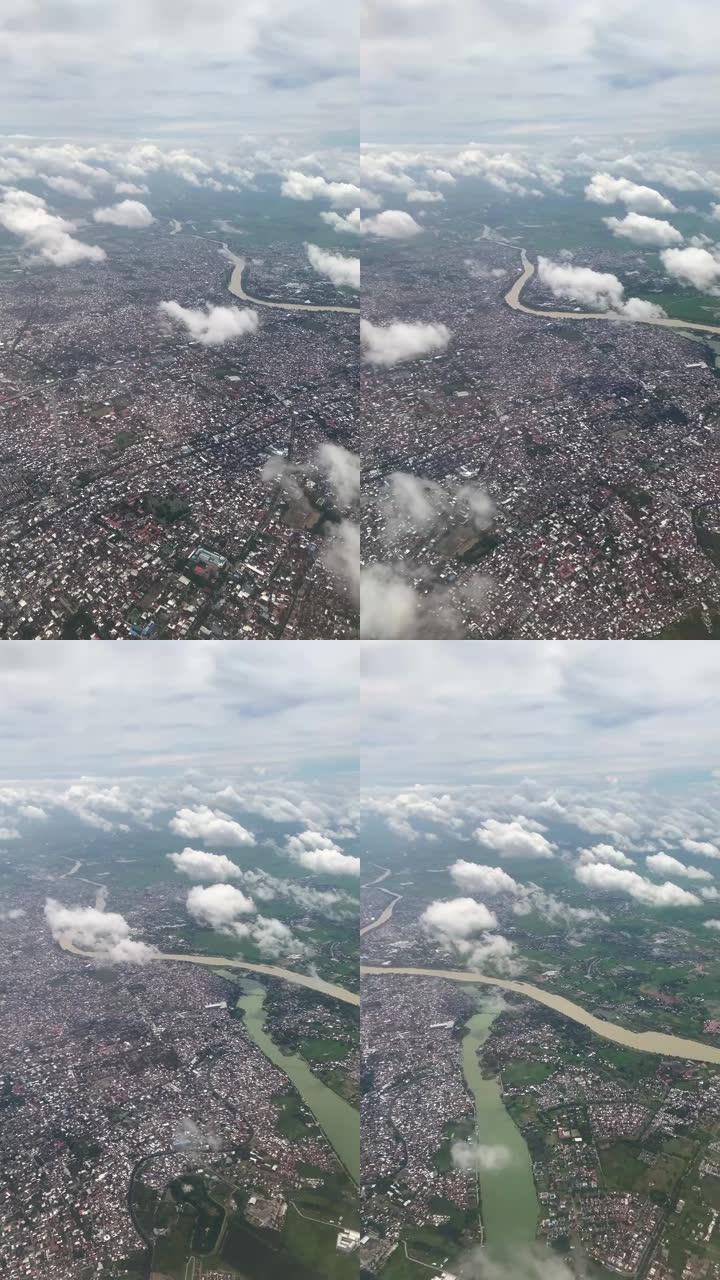 从天空中飞过云层的飞机上可以看到城市。飞机窗户上美丽风景的垂直视频。