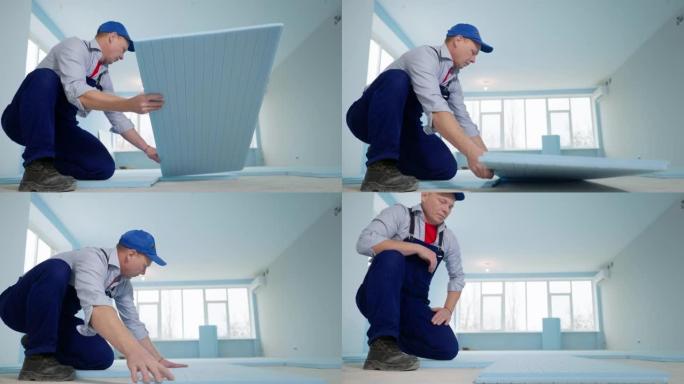 在新公寓里修理，穿着工作服的专业男子和地板上的帽子在房间里铺设发泡聚苯乙烯隔热材料