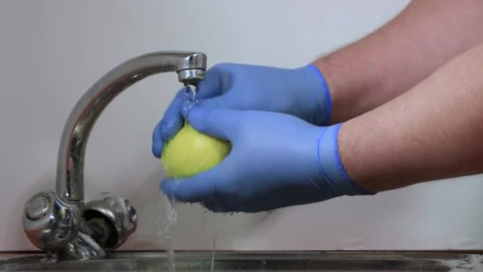 蓝手套的雄性手彻底冲洗黄色柠檬。