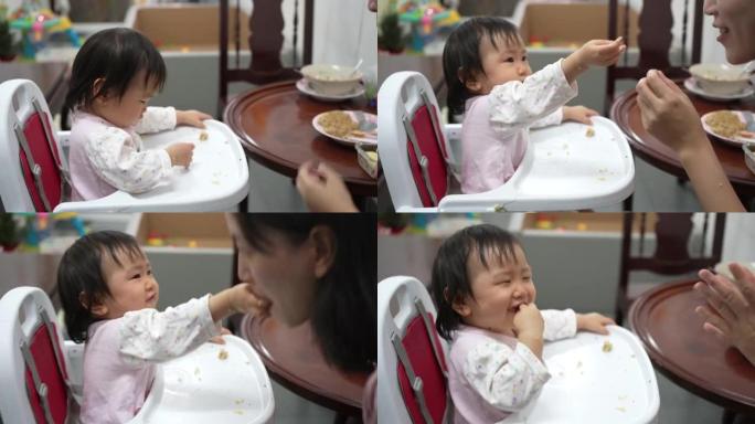 快乐的亚洲妈妈喂了小女孩。