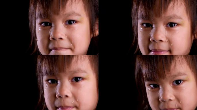 在家里的黑暗房间里，悲伤的小女孩哭泣的特写脸肖像。不幸童年的概念。