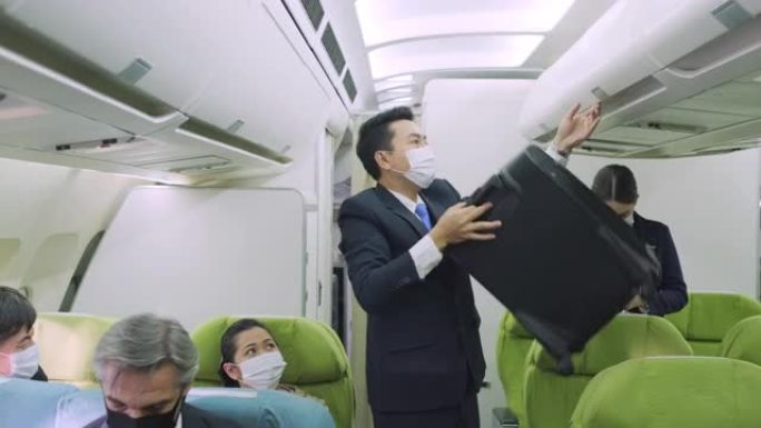 商务舱的飞行出勤帮助乘客将行李存放在飞机的机舱高架行李箱中。顶部隔层搁板上的随身行李箱。旅游和商业概