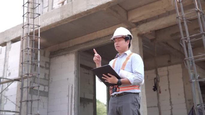 在建筑工地用数字平板电脑工作的亚洲工程师男性工人。