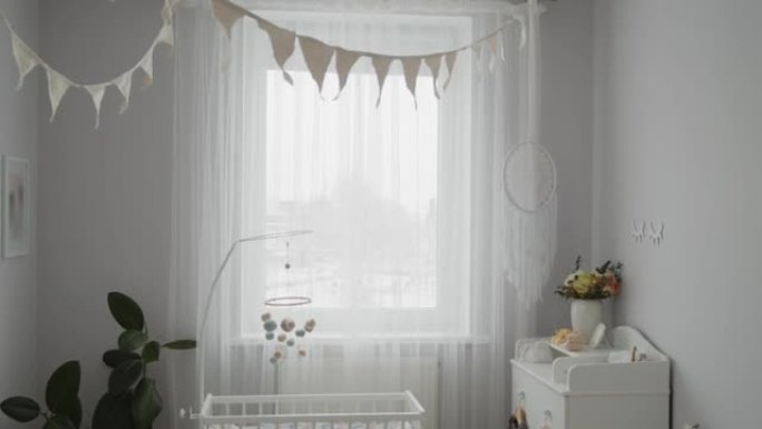 时尚明亮的现代婴儿房内部:婴儿床，悬挂移动，可更换的桌子