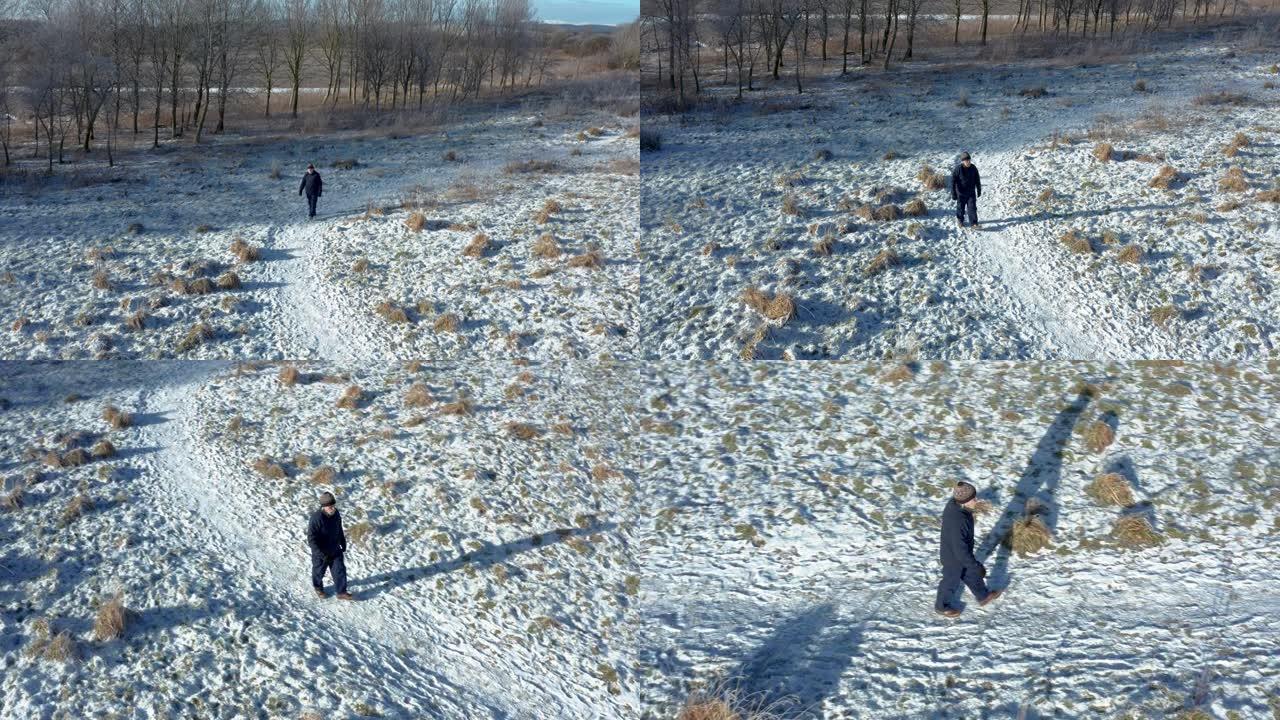 一架无人驾驶飞机追踪苏格兰西南部积雪覆盖的人行道上独自行走的一名高级男子的景色