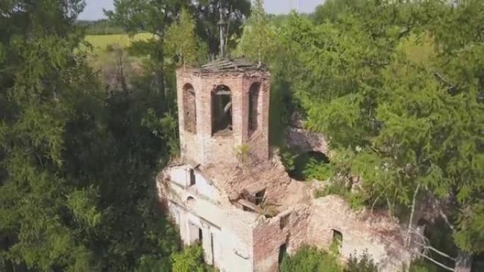 森林里被遗弃的教堂。夹。鸟瞰古老的教堂，钟楼和废墟的圆顶在明亮的阳光的绿色树木的背景下