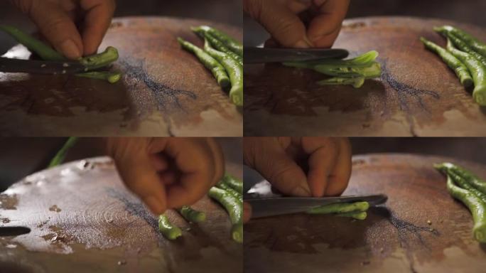 绿色辣椒被老太太用烹饪刀切碎。准备烹饪健康菜单。