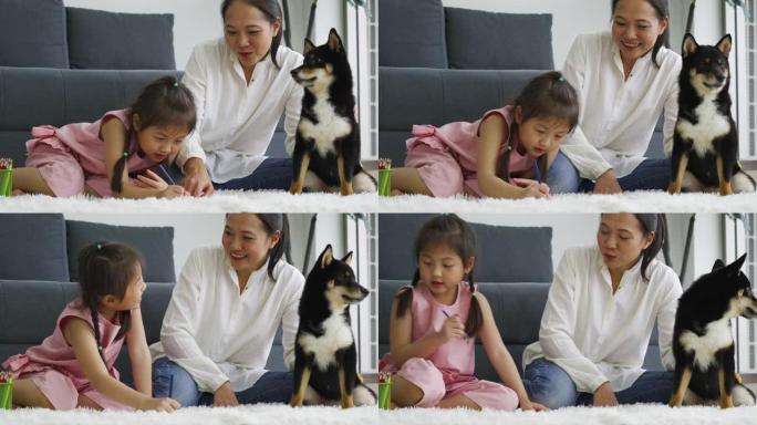 亚洲母女和他们的狗画画。家庭在室内休息。