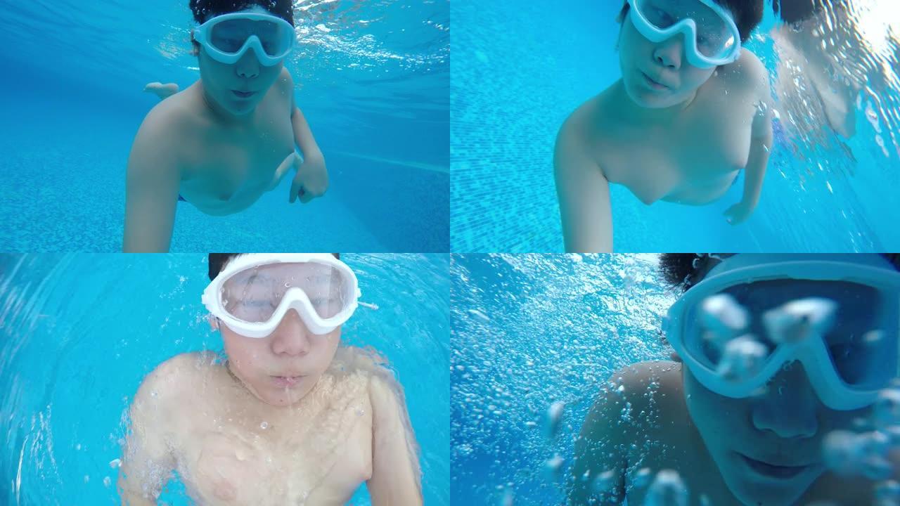 快乐的亚洲男孩在游泳池游泳，水下射击。