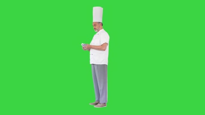 穿着制服的高级厨师在绿屏上数钱，色键